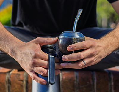Un voyageur dégustant un maté en déplacement, la bombilla plongée dans la calebasse, symbolisant l'énergie et la convivialité de cette boisson nomade